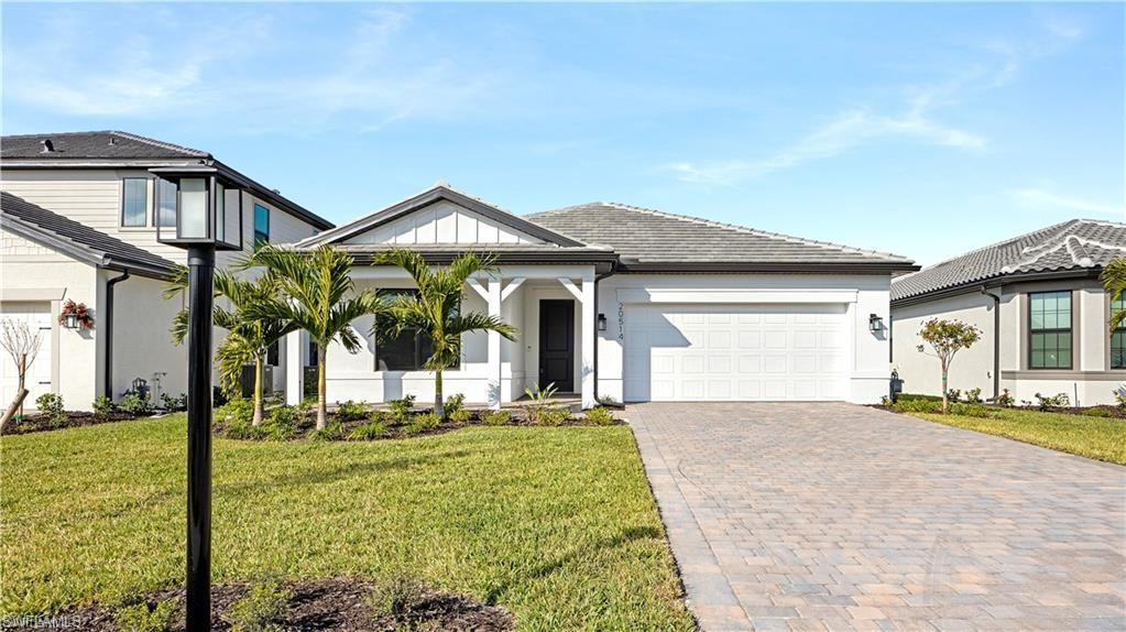 View of front facade with decorative driveway, a front yard, an attached garage, and stucco siding