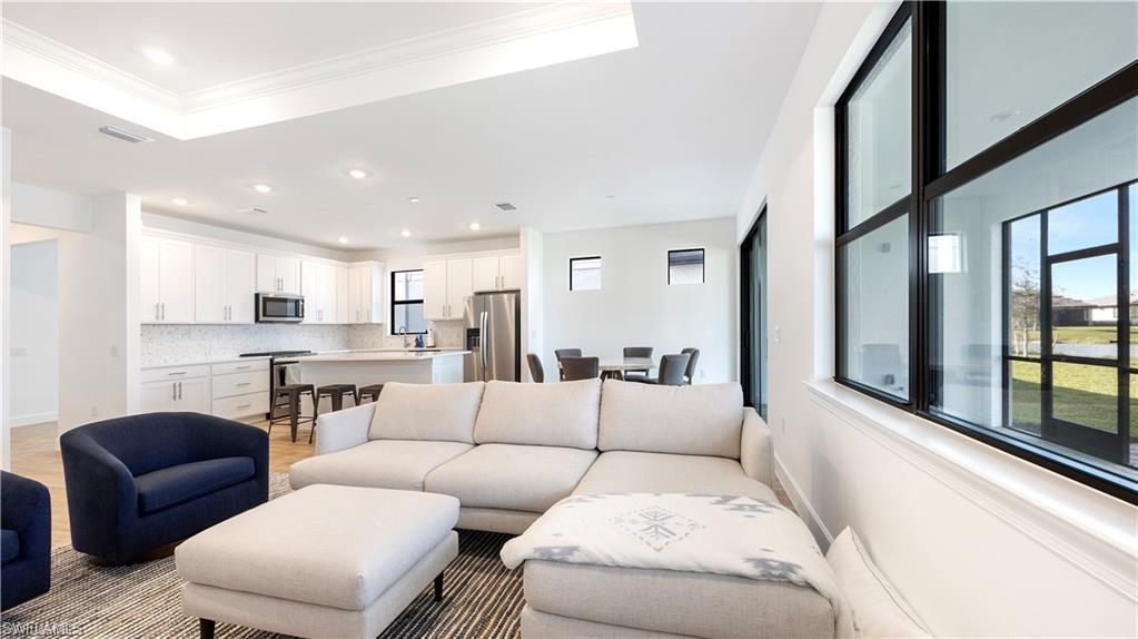 Living area featuring a tray ceiling, recessed lighting, and crown molding