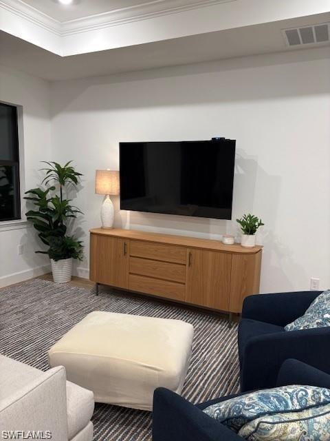 Living area featuring a raised ceiling and ornamental molding