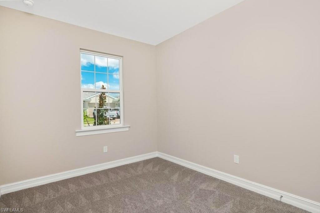 Carpeted spare room featuring baseboards
