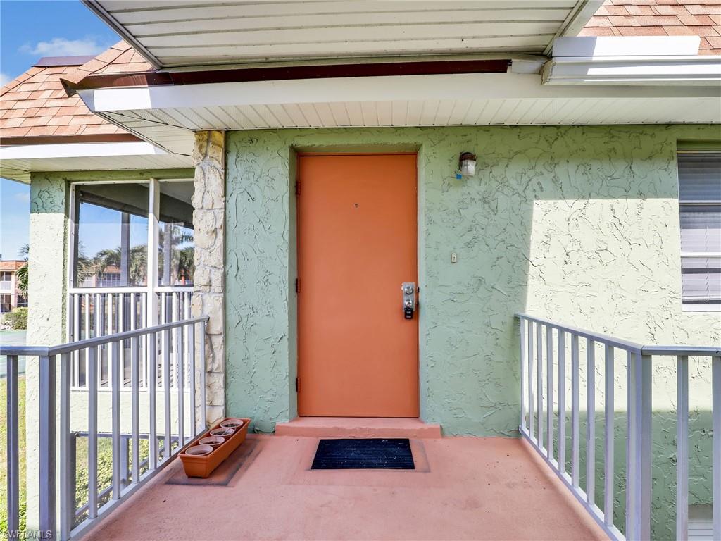 Property entrance featuring stucco siding and roof with shingles