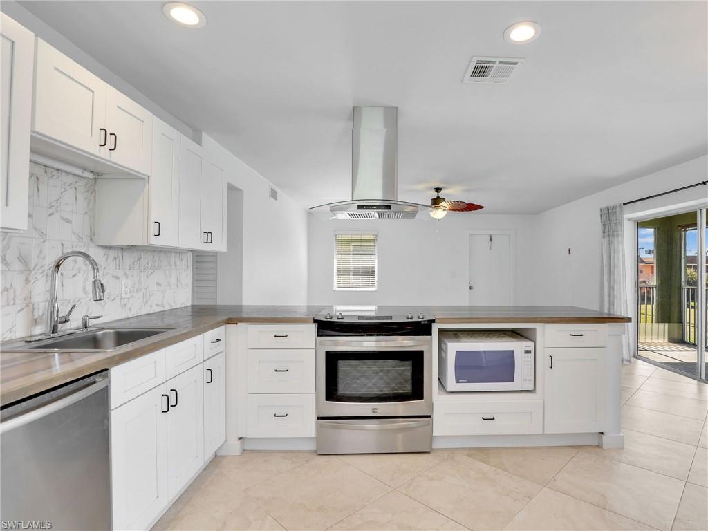 Kitchen with stainless steel appliances, a peninsula, white cabinetry, and recessed lighting