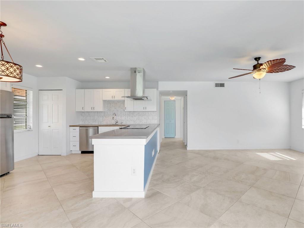 Kitchen featuring plenty of natural light, white cabinets, island exhaust hood, appliances with stainless steel finishes, and recessed lighting