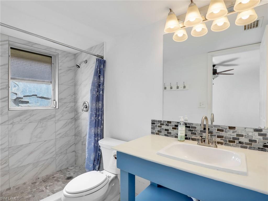 Full bath with decorative backsplash, a stall shower, vanity, and ceiling fan
