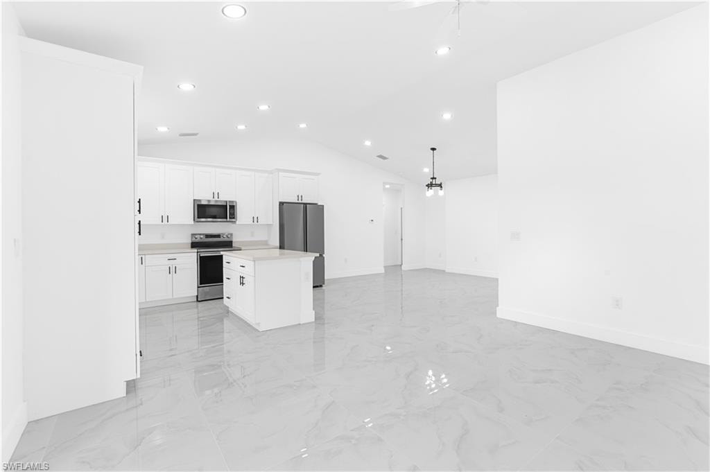 Kitchen with white cabinets, a kitchen island, light countertops, appliances with stainless steel finishes, and open floor plan