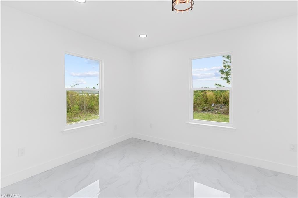 Empty room with plenty of natural light, recessed lighting, and marble finish flooring