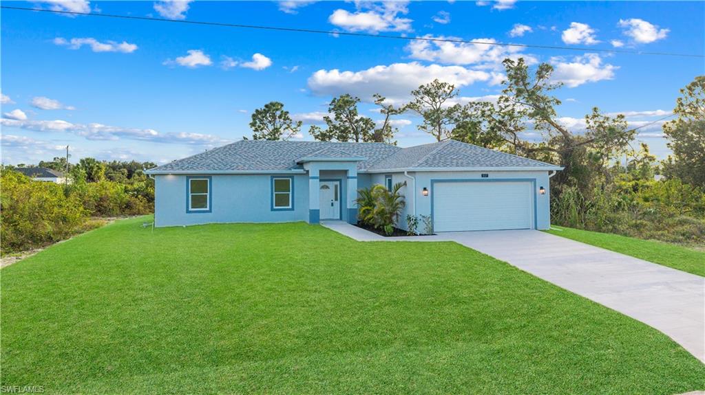 Ranch-style home with a front yard, concrete driveway, stucco siding, and a garage