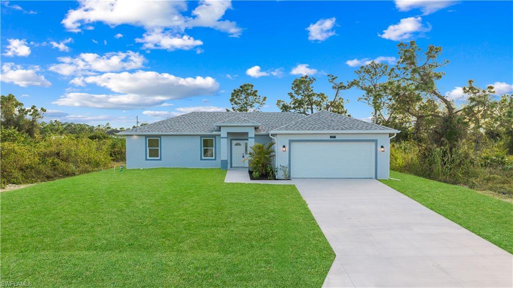 View of front of property featuring driveway, a front yard, stucco siding, and an attached garage