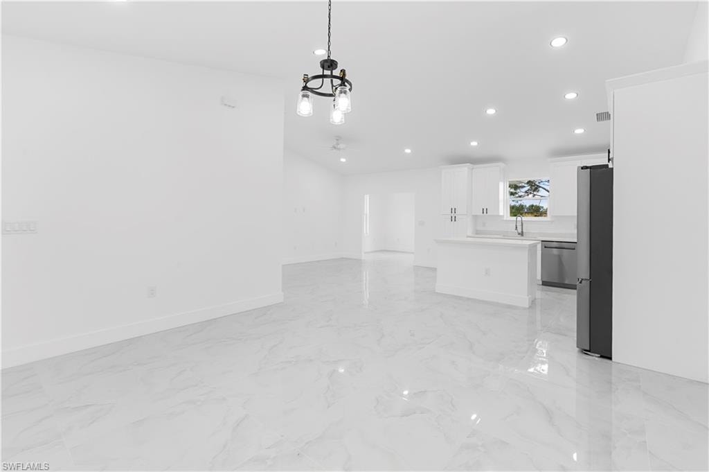 Unfurnished living room with recessed lighting, light marble finish flooring, a chandelier, and ceiling fan