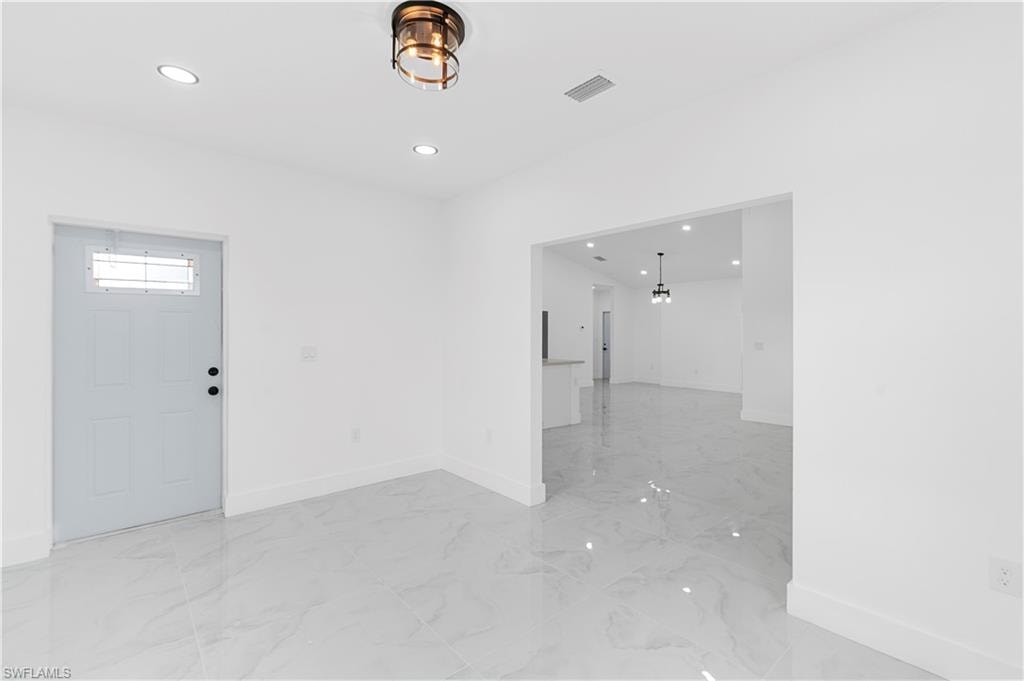 Entryway featuring light marble finish flooring, recessed lighting, and a chandelier