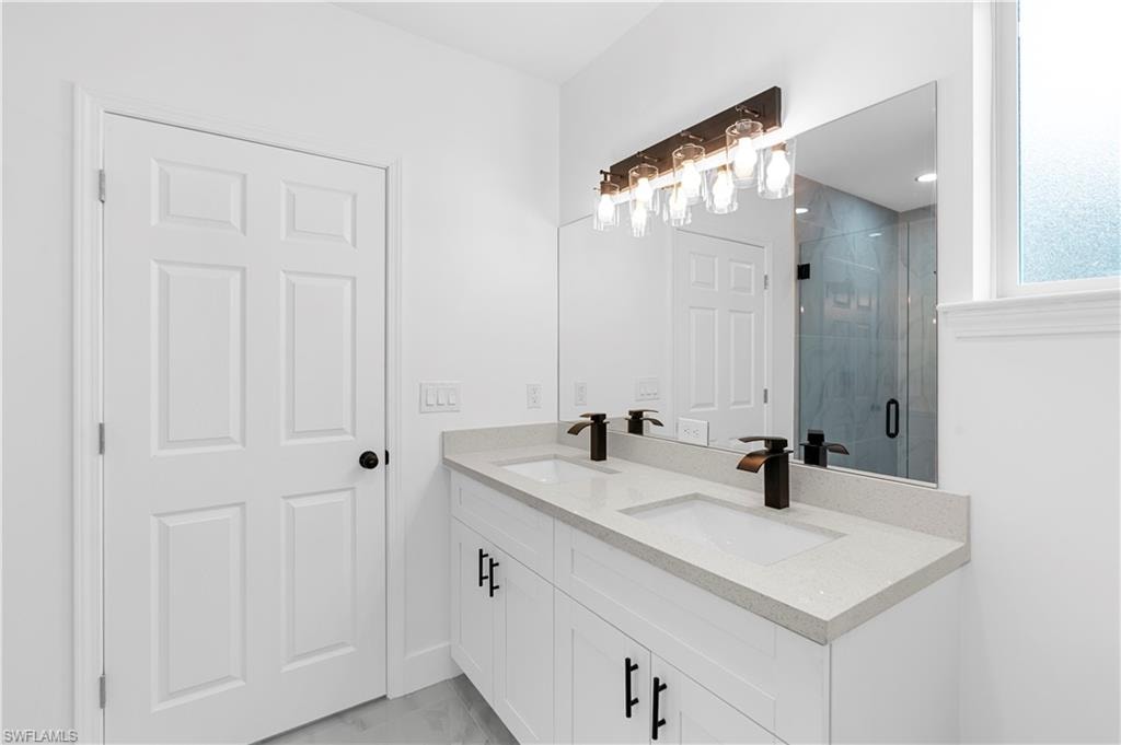 Full bath featuring double vanity and a shower stall