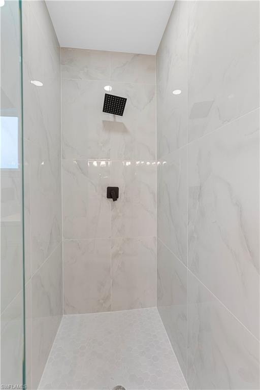 Full bath with a marble finish shower