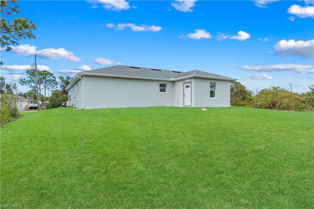 Rear view of house with a yard and stucco siding
