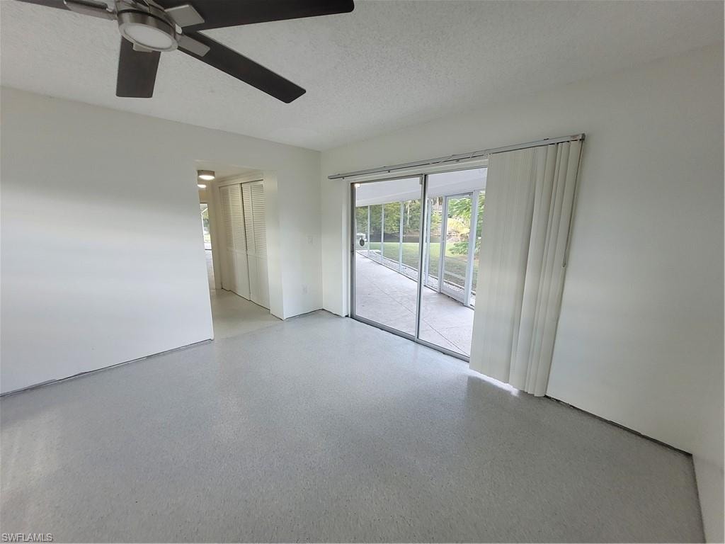 Unfurnished room featuring a textured ceiling, speckled floor, and a ceiling fan