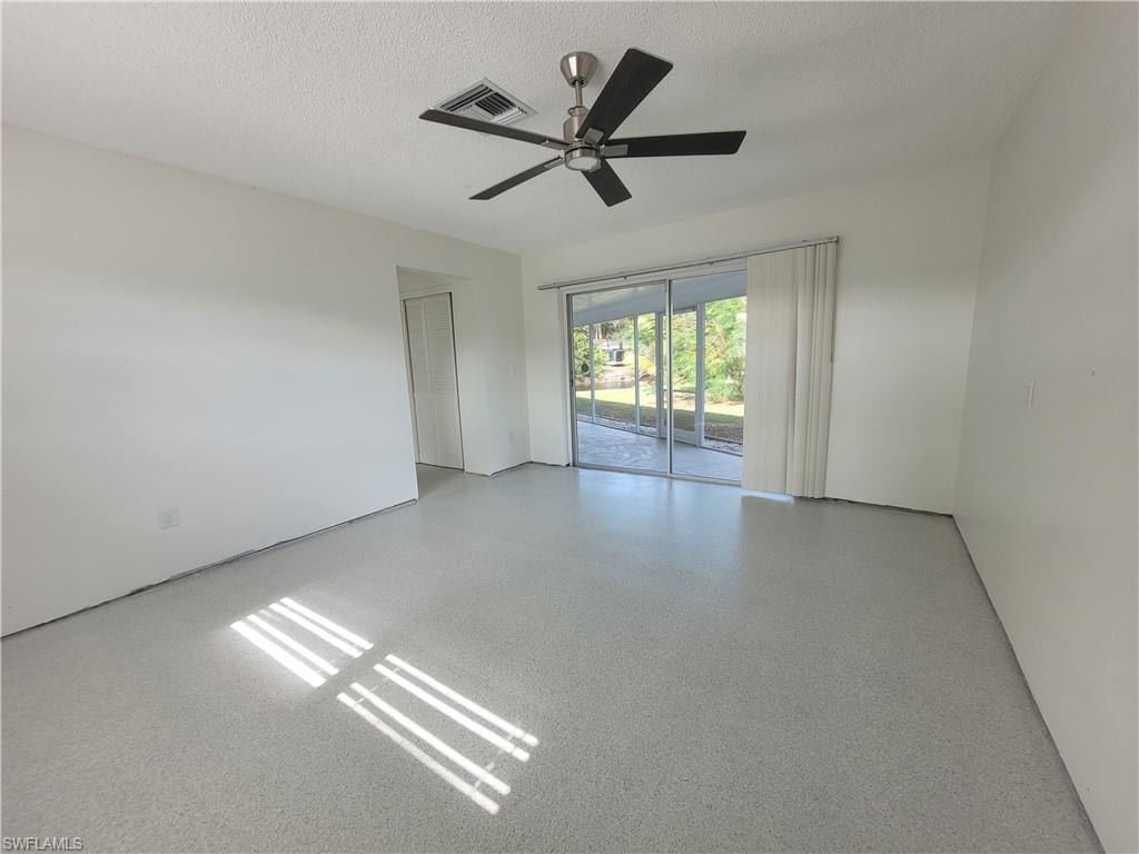 Spare room with speckle patterned floor, a textured ceiling, and ceiling fan