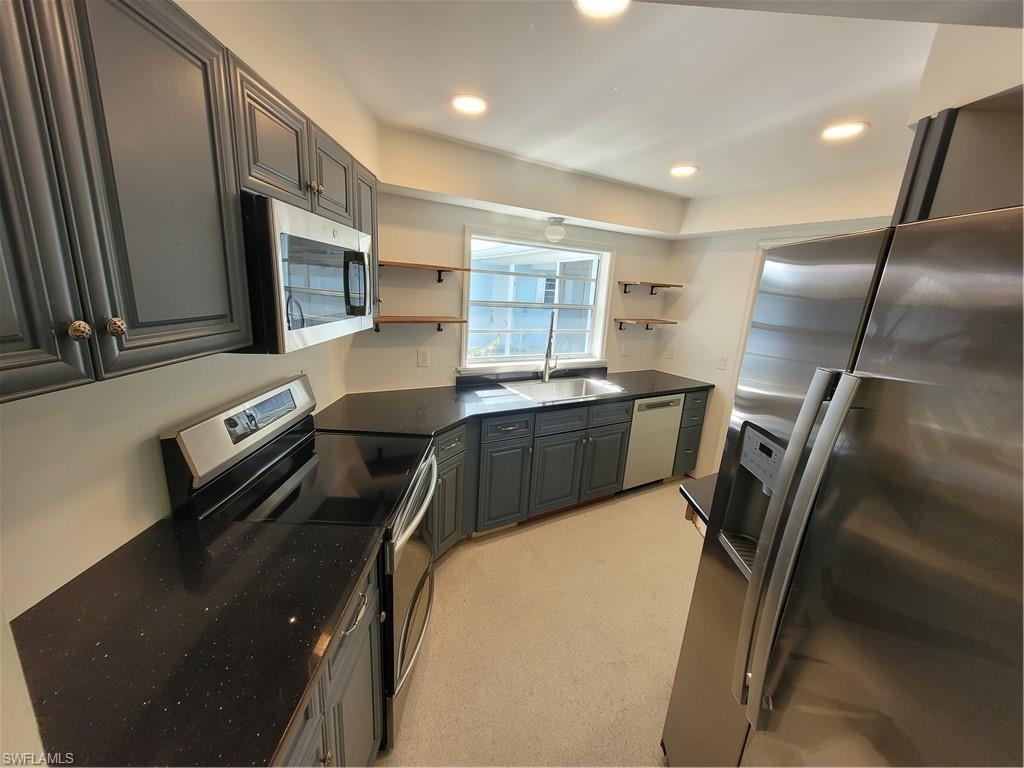 Kitchen with stainless steel appliances, open shelves, recessed lighting, gray cabinets, and dark stone counters