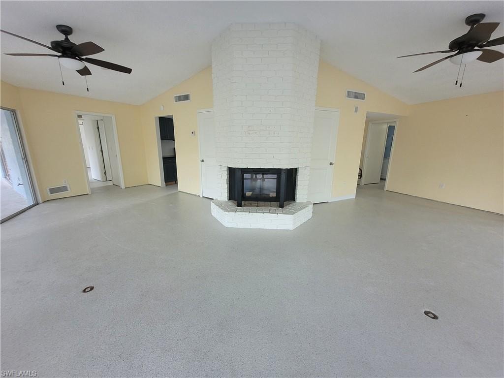 Unfurnished living room featuring ceiling fan, a fireplace, and high vaulted ceiling