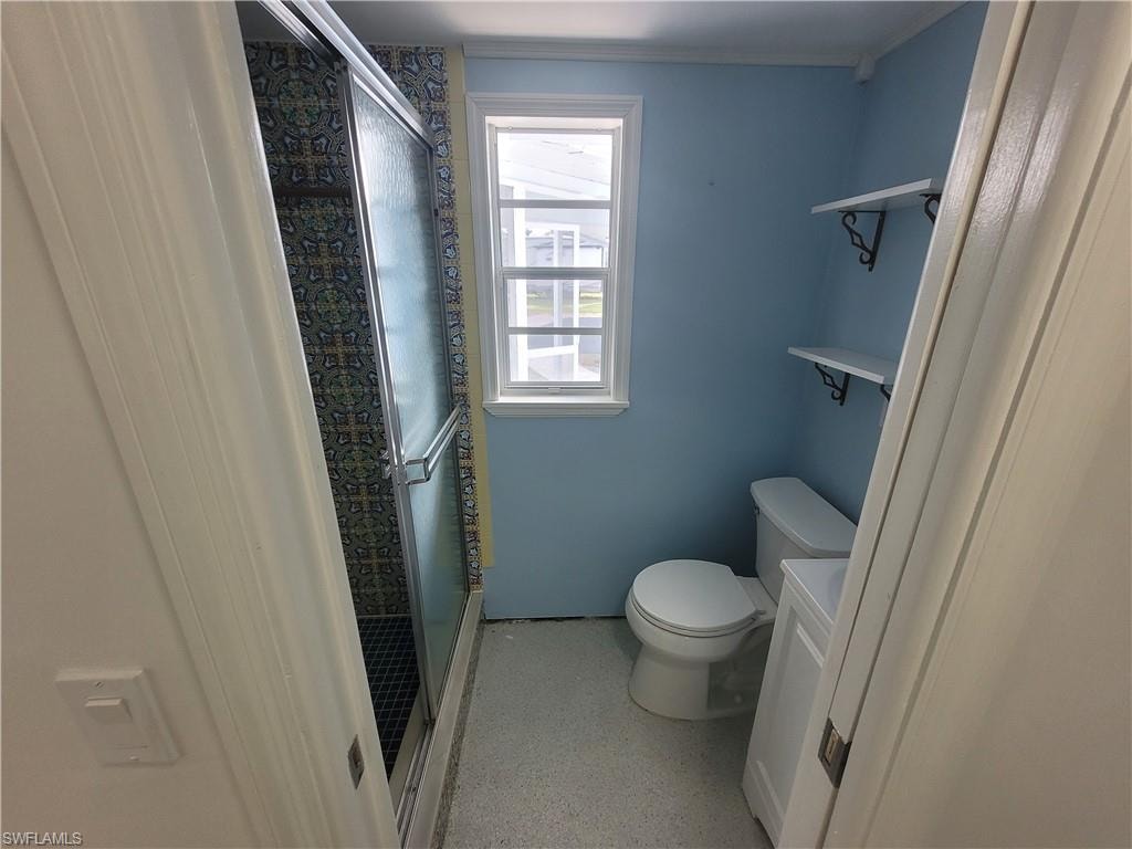 Bathroom featuring a shower stall, vanity, and crown molding