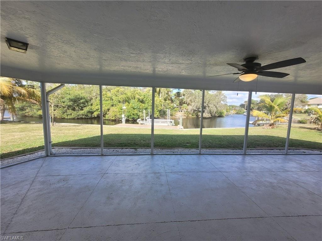 Unfurnished sunroom featuring ceiling fan and a water view