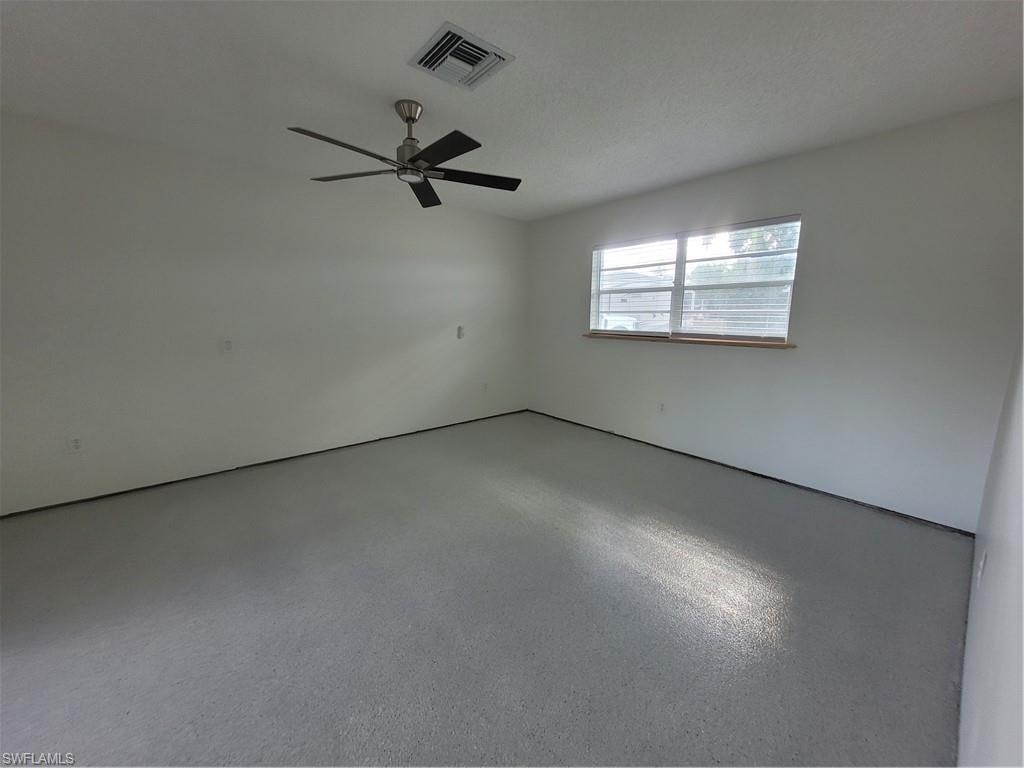 Empty room with a textured ceiling, ceiling fan, and speckle patterned floor