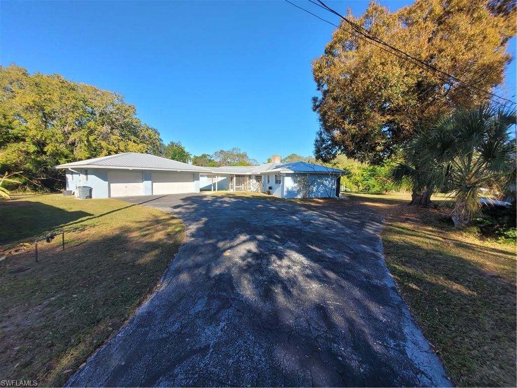 Ranch-style house with a front yard, asphalt driveway, and a metal roof