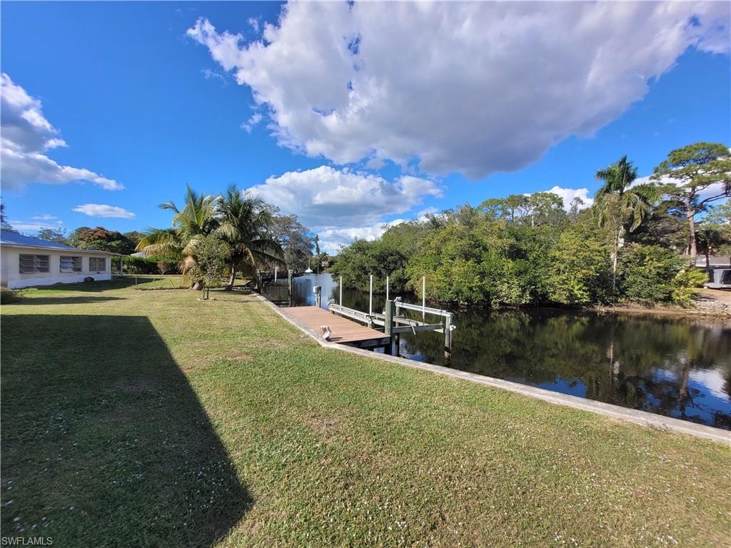 Dock featuring a lawn, boat lift, and a water view