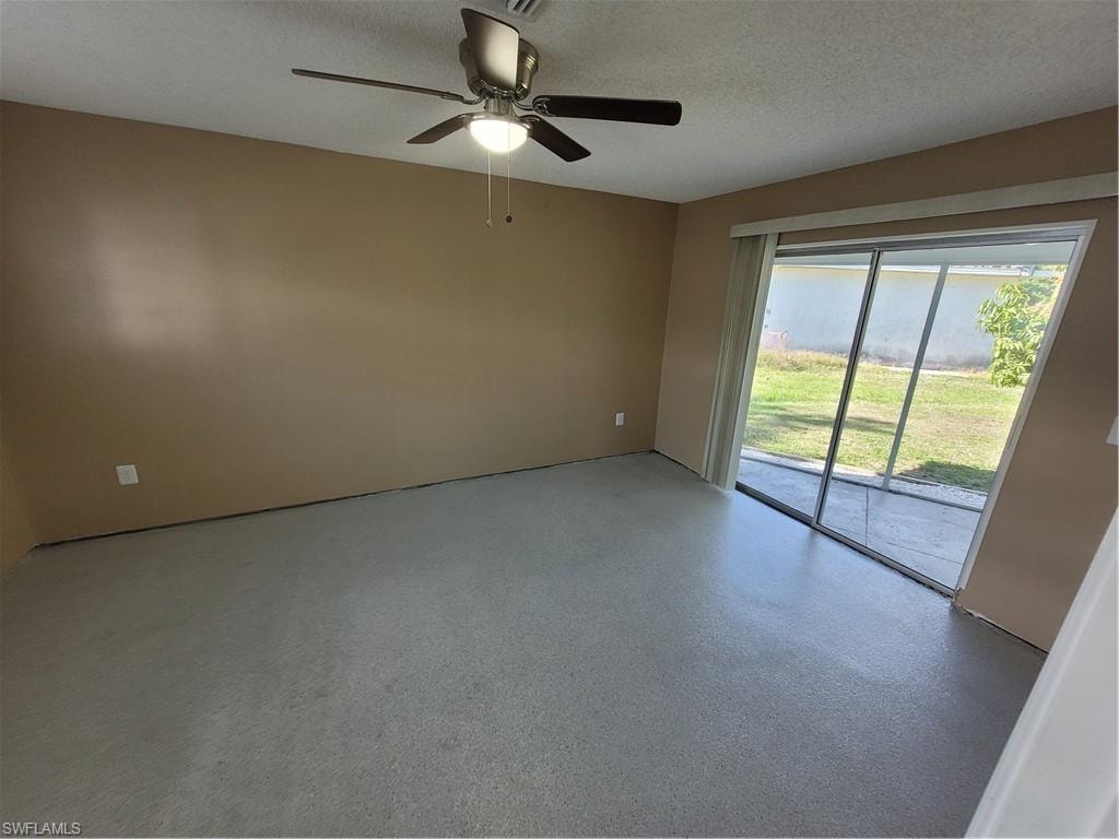 Spare room featuring a textured ceiling, ceiling fan, and speckle patterned floor