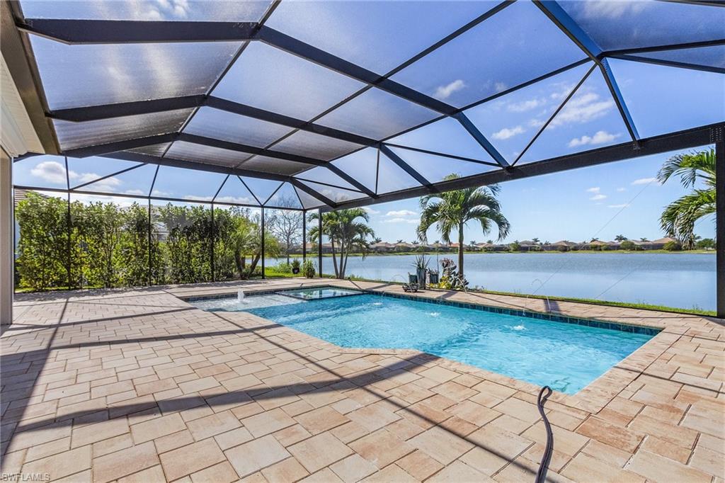 View of swimming pool featuring a sunroom, a water view, screen enclosure, a patio area, and a pool with connected hot tub