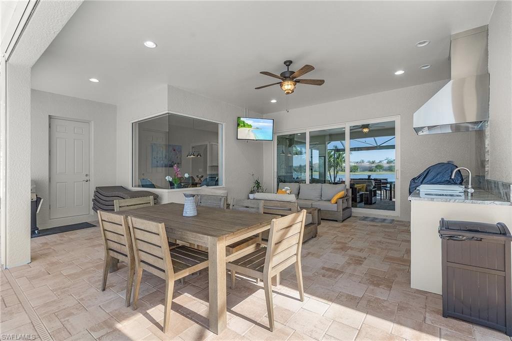 Outdoor Dining room with a sunroom, ceiling fan, recessed lighting, and light stone finish floors