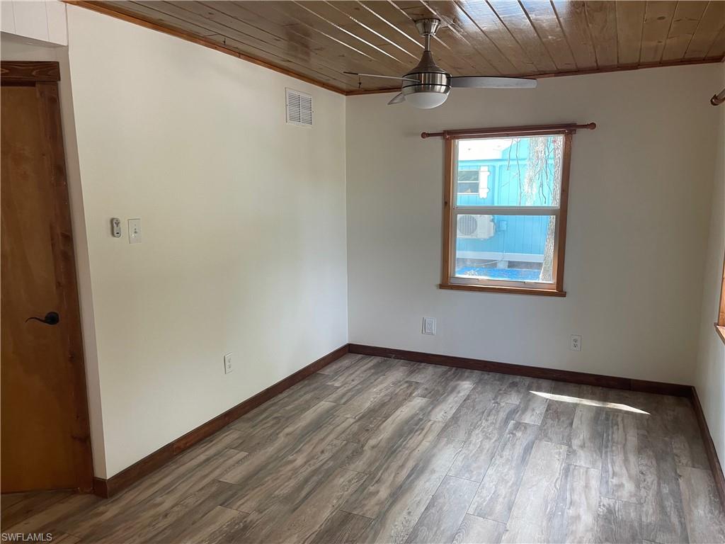 Unfurnished room with wooden ceiling, wood finished floors, ceiling fan, and crown molding