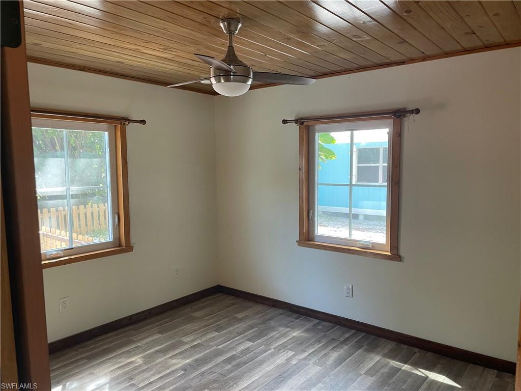 Empty room with wooden ceiling, wood finished floors, a ceiling fan, and healthy amount of natural light