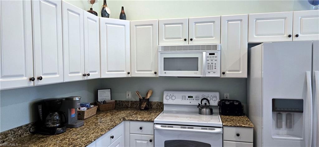 Kitchen featuring white appliances, white cabinetry.