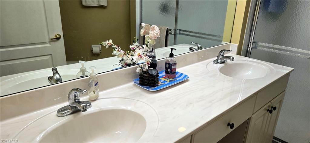 Full bath featuring double vanity and a shower with door