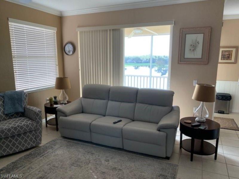 Living area with crown molding and light tile patterned floors