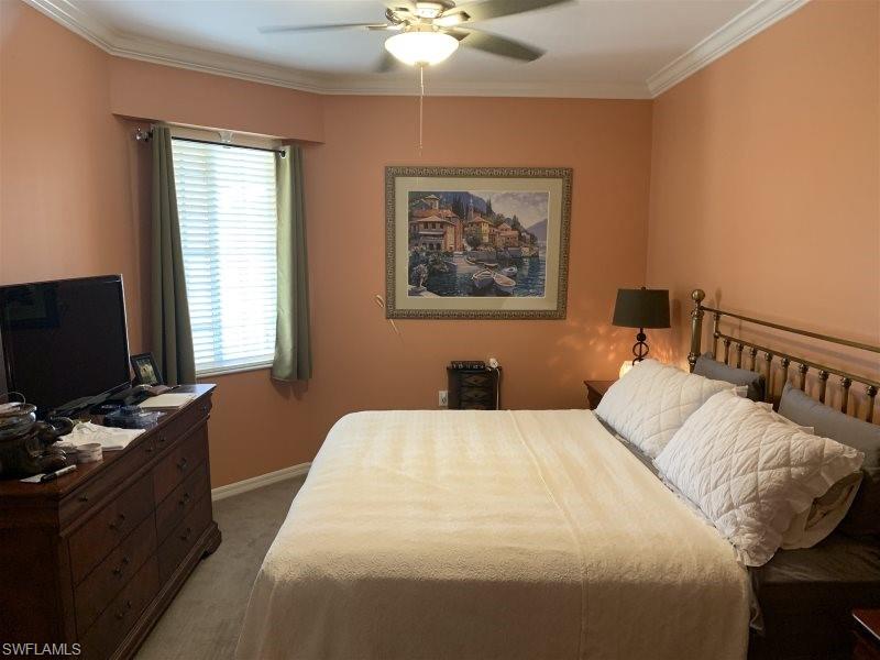 Bedroom featuring light carpet, ornamental molding, and ceiling fan