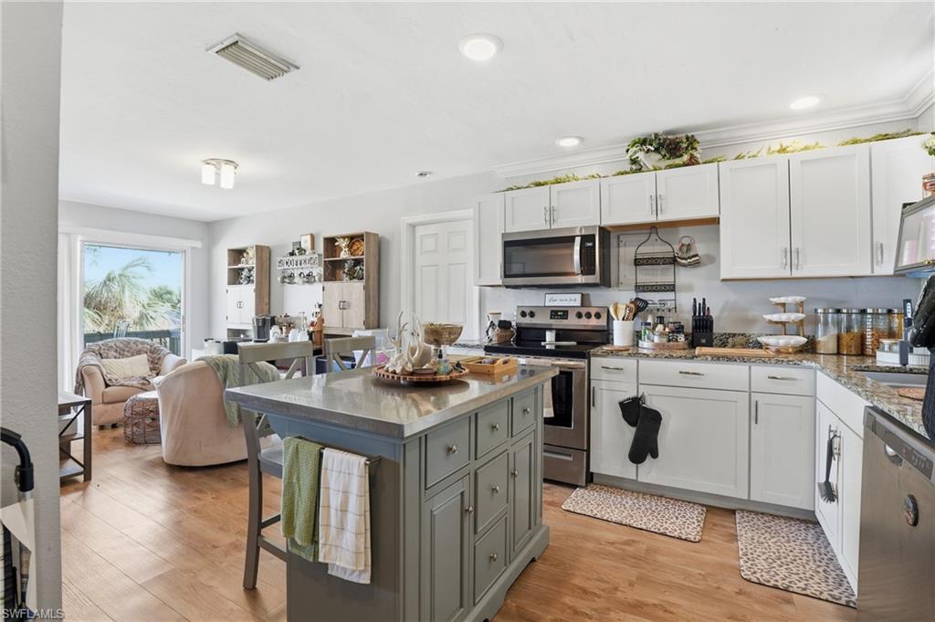 Kitchen with white cabinets, appliances with stainless steel finishes, a breakfast bar area, and recessed lighting