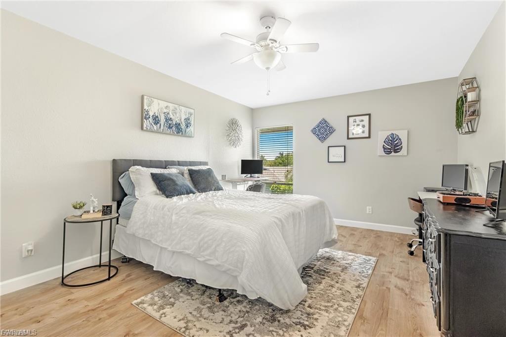Bedroom featuring a desk, light wood-style flooring, and ceiling fan