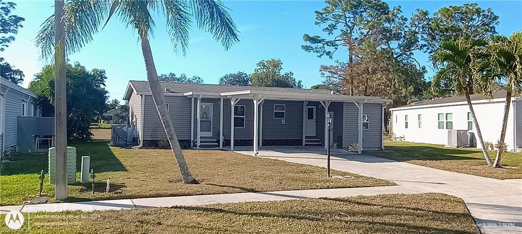 Manufactured / mobile home featuring a front lawn, driveway, and a carport