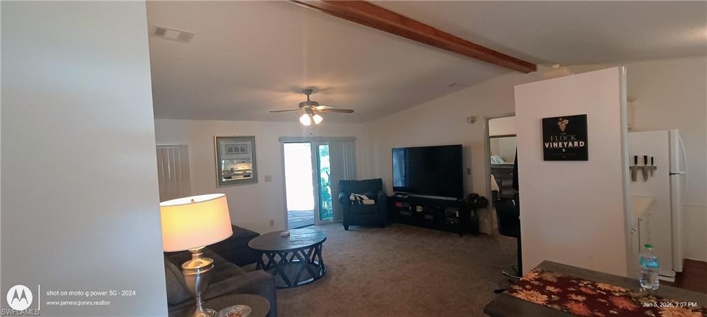 Carpeted living area featuring ceiling fan