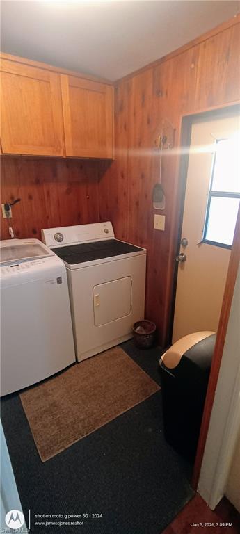 Laundry room with wooden walls and washer and clothes dryer