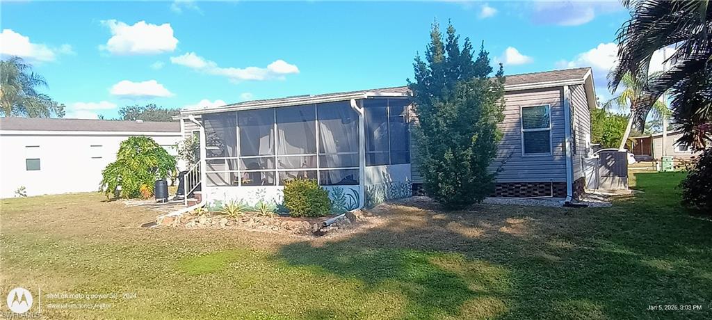 Rear view of property featuring a sunroom and a yard