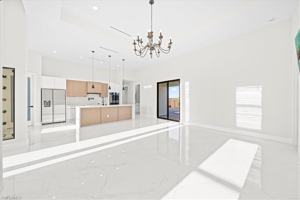 Hall featuring a barn door, a chandelier, light marble finish flooring, and a high tray ceiling