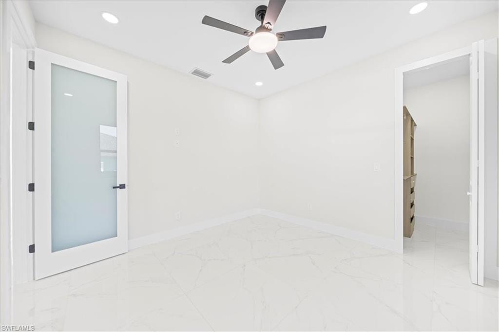Empty room featuring light marble finish floors and suspended lighting