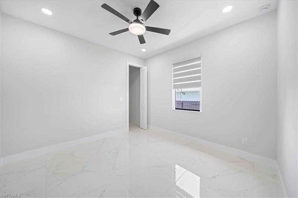 Empty room featuring recessed lighting, light marble finish flooring, ceiling fan, and a raised ceiling