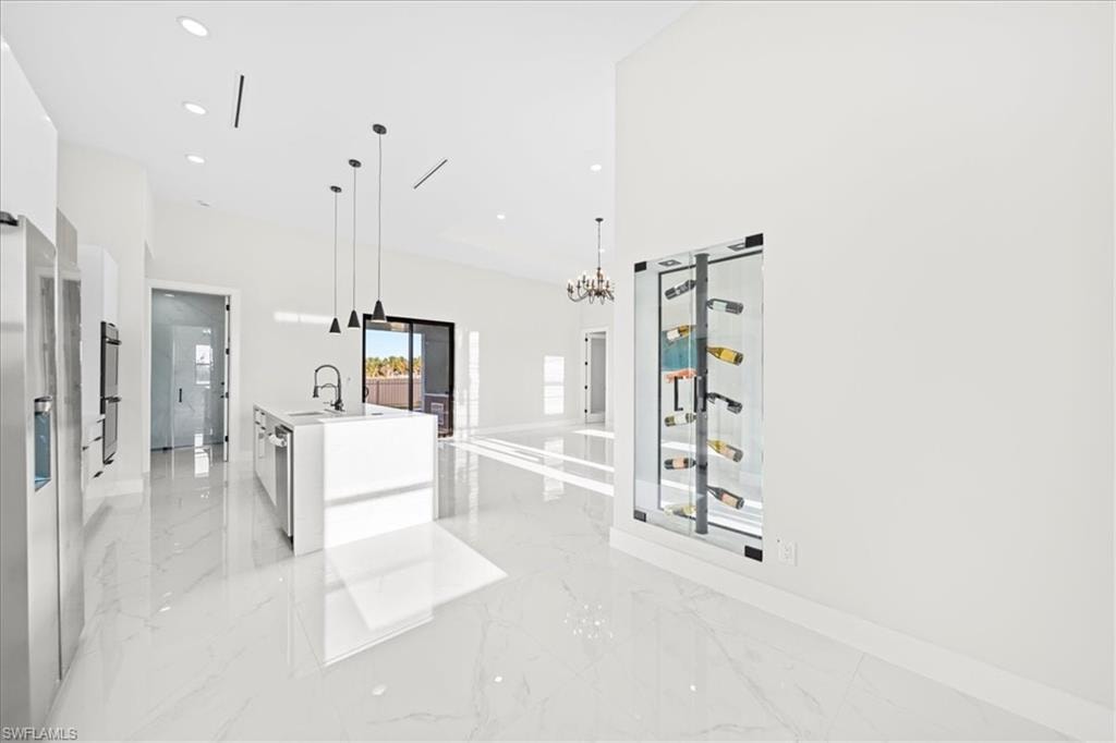 Kitchen featuring suspended lighting, a barn door, open floor plan, light marble finish floors, and modern cabinets