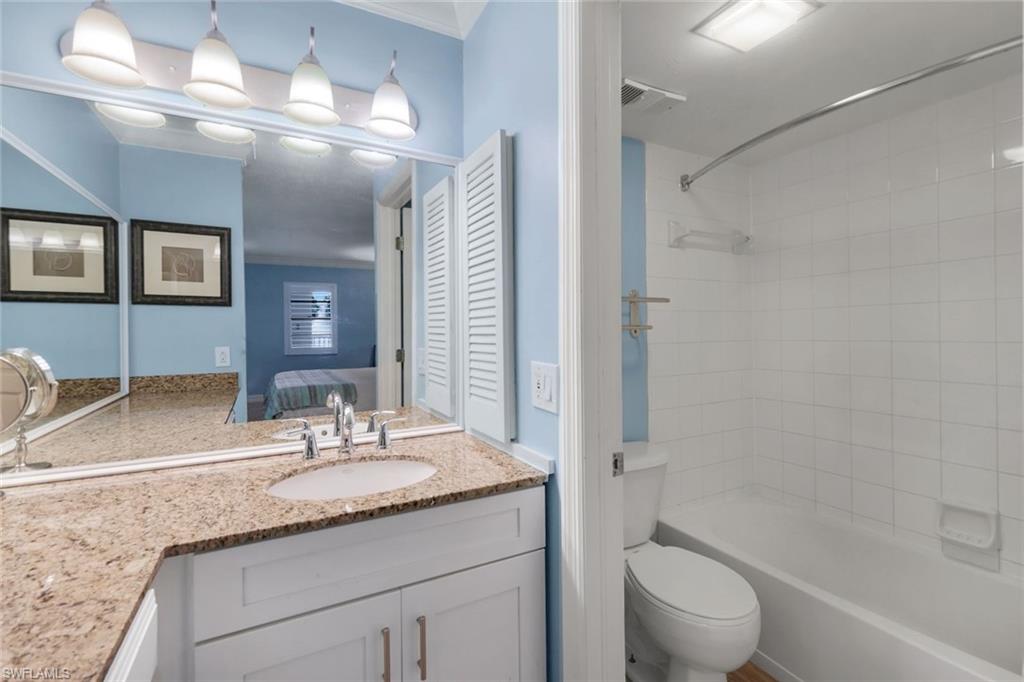 Full bathroom featuring tiled shower / bath combo, vanity, crown molding, and toilet