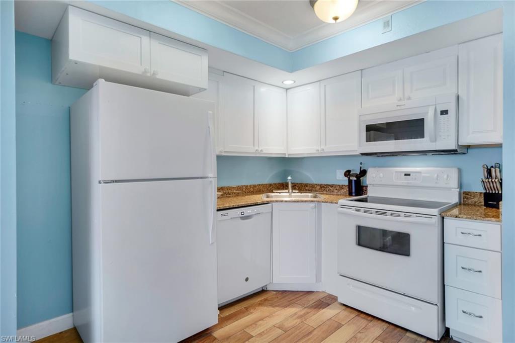 Kitchen with crown molding, sink, white cabinets, and white appliances
