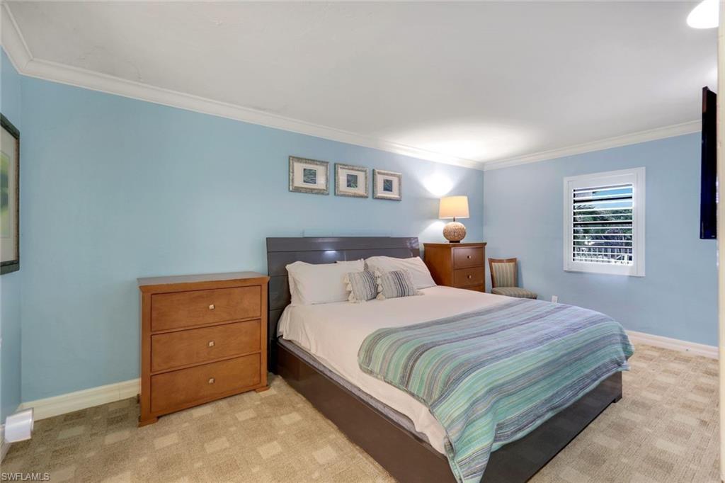 Bedroom with light colored carpet and ornamental molding