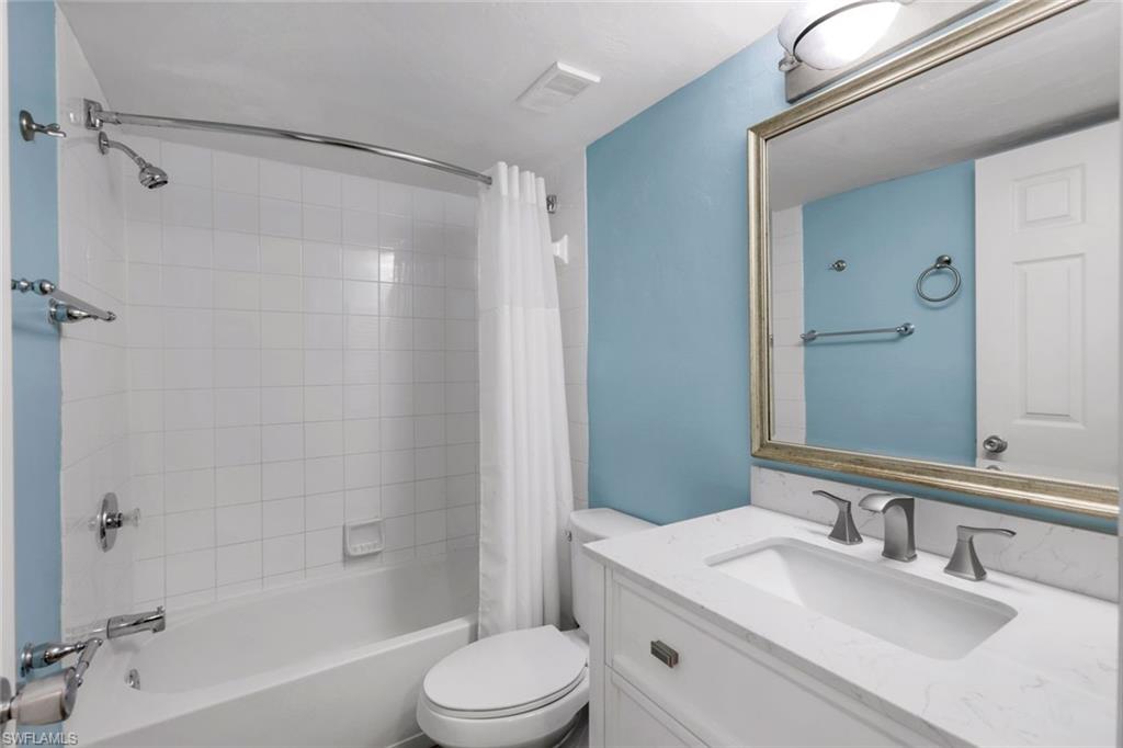 Full bathroom featuring vanity, shower / bath combination with curtain, and toilet