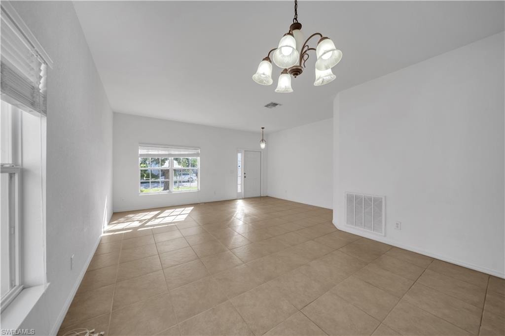 Unfurnished room featuring a chandelier and light tile patterned floors